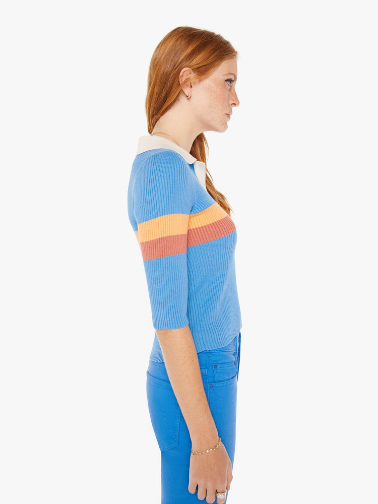 Side view of a woman blue with orange stripes collared blouse with a V-neck, elbow-length sleeves and a narrow fit.