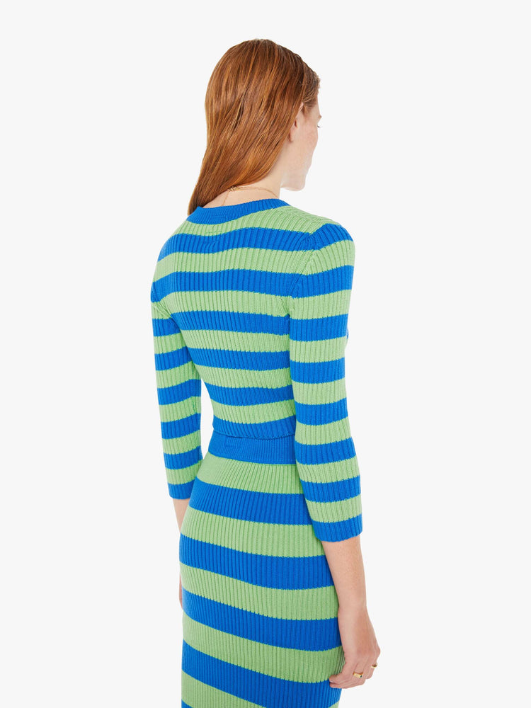 A back view of a woman wearing a green and blue striped cardigan featuring cropped body and sleeves.