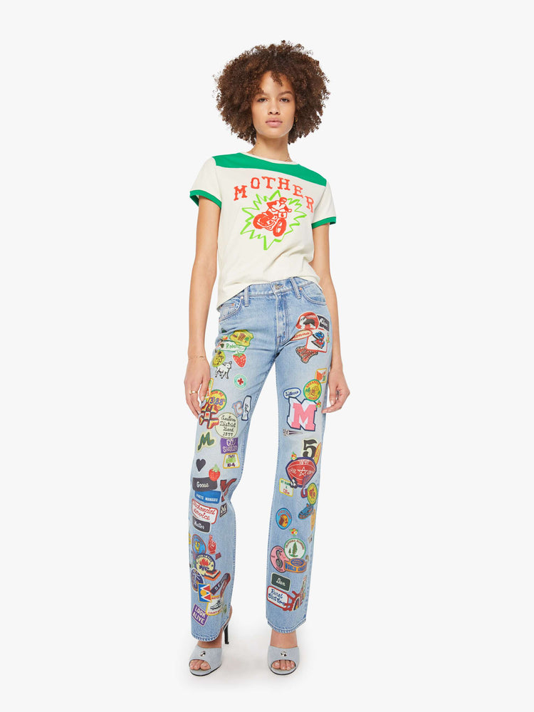 Full body view of a woman in an off-white with green details tee and features a hand-drawn motorcycle graphic and MOTHER's name in pink fuzzy text on the chest.