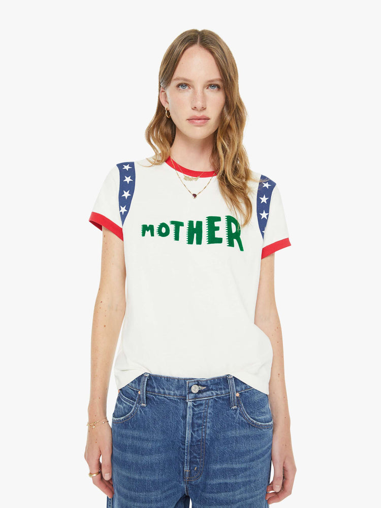 Front view of a woman in an off-white, the tee with white stars along the sleeves, red trim and MOTHER's name in green across the front — finished with a raised, velvety flocked texture.