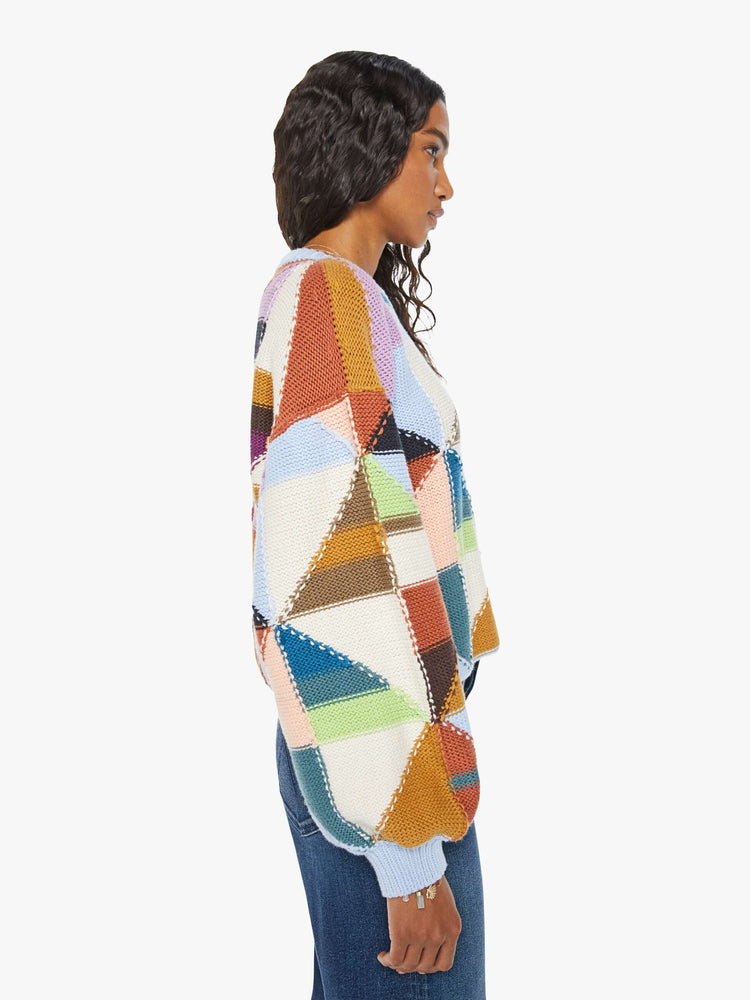 Side view of a womens multi color block sweater featuring a cropped body and billow sleeves.