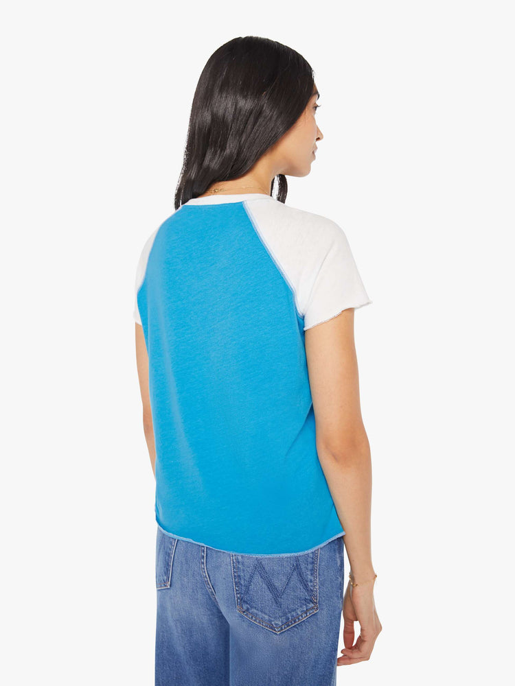 Back  view of a woman in a  bright blue with white sleeves tee and navy block text on the front.
