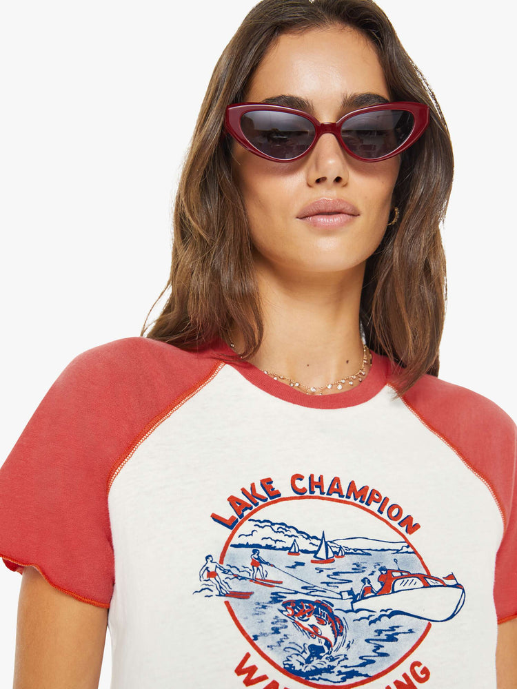 Close up view of a woman in a white tee with faded red sleeves and an airbrushed water skiing graphic on the front.