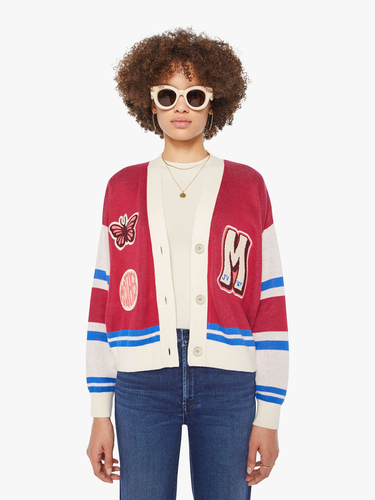 Front view of a woman in a faded red with athletic-inspired stripes across the sleeves  V-neck cardigan with drop shoulders.