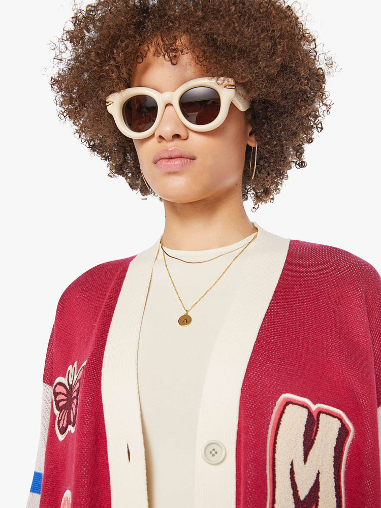 Close up view of a woman in a faded red with athletic-inspired stripes across the sleeves  V-neck cardigan with drop shoulders.