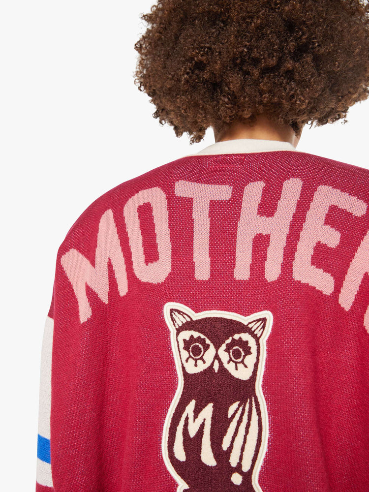 Back view of a woman in a faded red with athletic-inspired stripes across the sleeves  V-neck cardigan with drop shoulders.