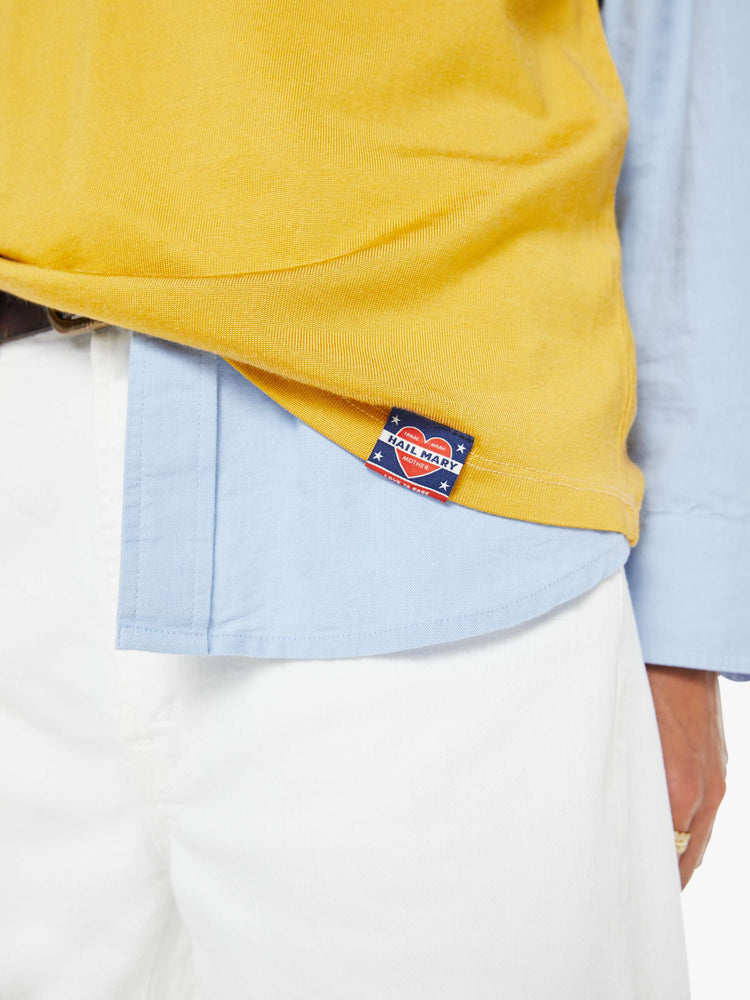 Swatch view of a woman in yellow tee features navy and white stripes at the neck, shoulder and sleeves, and a white text appliqued on the front inspired by a sports jersey.