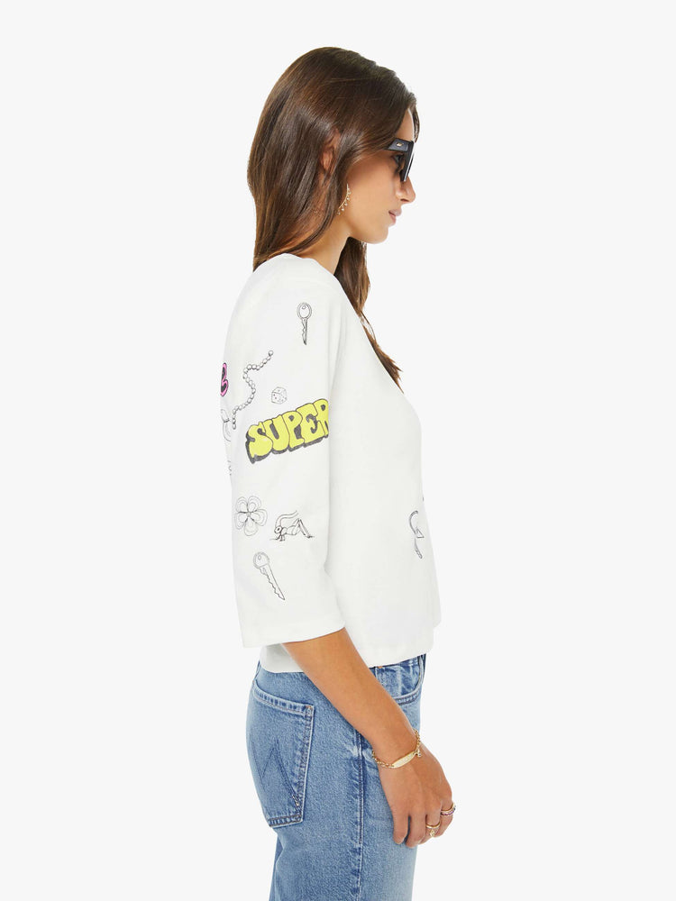 Side view of a woman in a white with colorful butterfly crewneck tee with elbow-length sleeves and a loose, boxy fit.