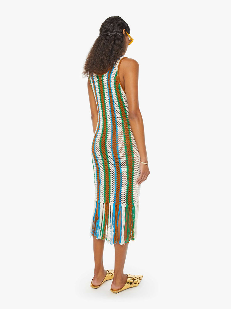 Back view of a woman in a sleeveless vertical multi-colored striped midi dress with a scoop neck, narrow fit and fringed hem.