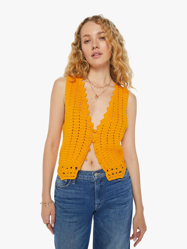 Front view of a woman in a golden yellow V-neck vest with a button closure, angled hems and openwork details.