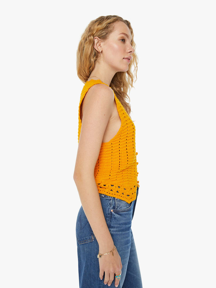 Side view of a woman in a golden yellow V-neck vest with a button closure, angled hems and openwork details.