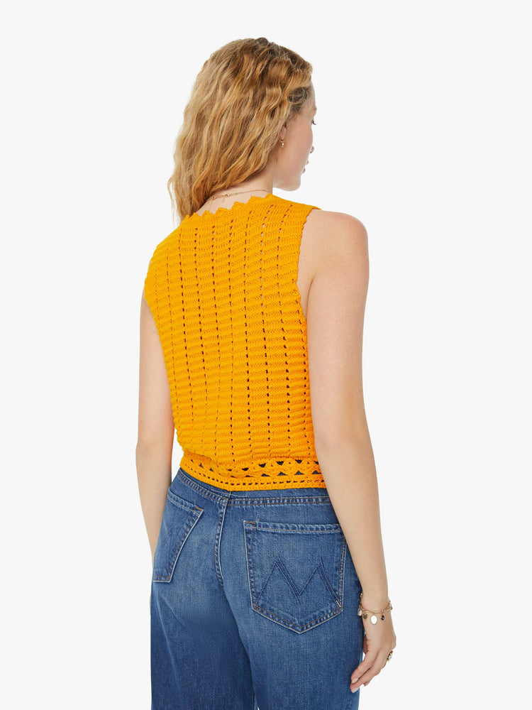 Back view of a woman in a golden yellow V-neck vest with a button closure, angled hems and openwork details.