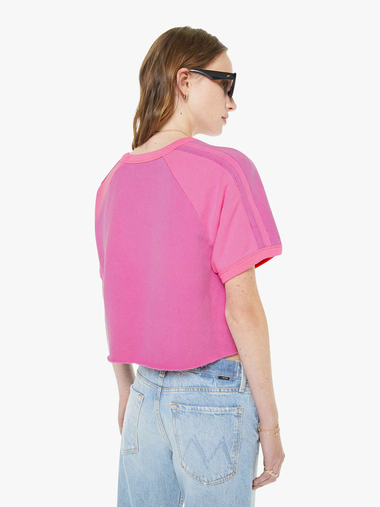 Back view of a woman in a pink with lighter panels with horizontal stripes at the shoulders.