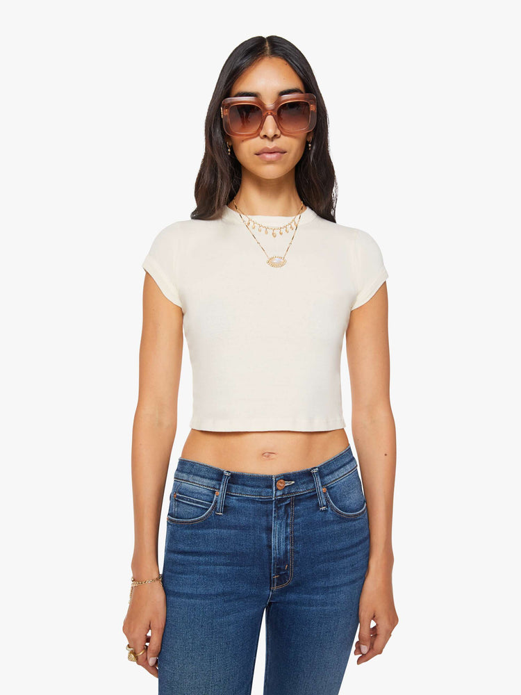 Front view of a woman in an off white crewneck tee with extra-short sleeves and a narrow fit.