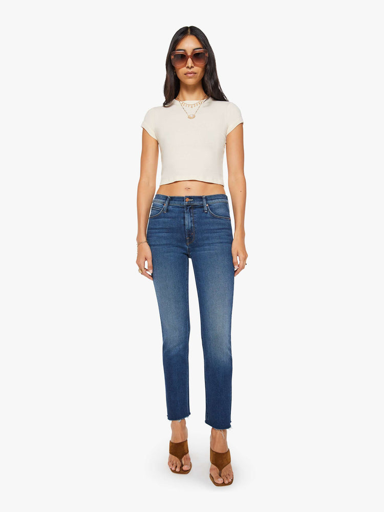 Full body view of a woman in an off white crewneck tee with extra-short sleeves and a narrow fit.