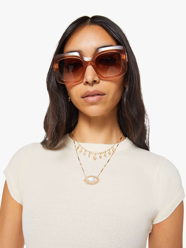 Close up view of a woman in an off white crewneck tee with extra-short sleeves and a narrow fit.