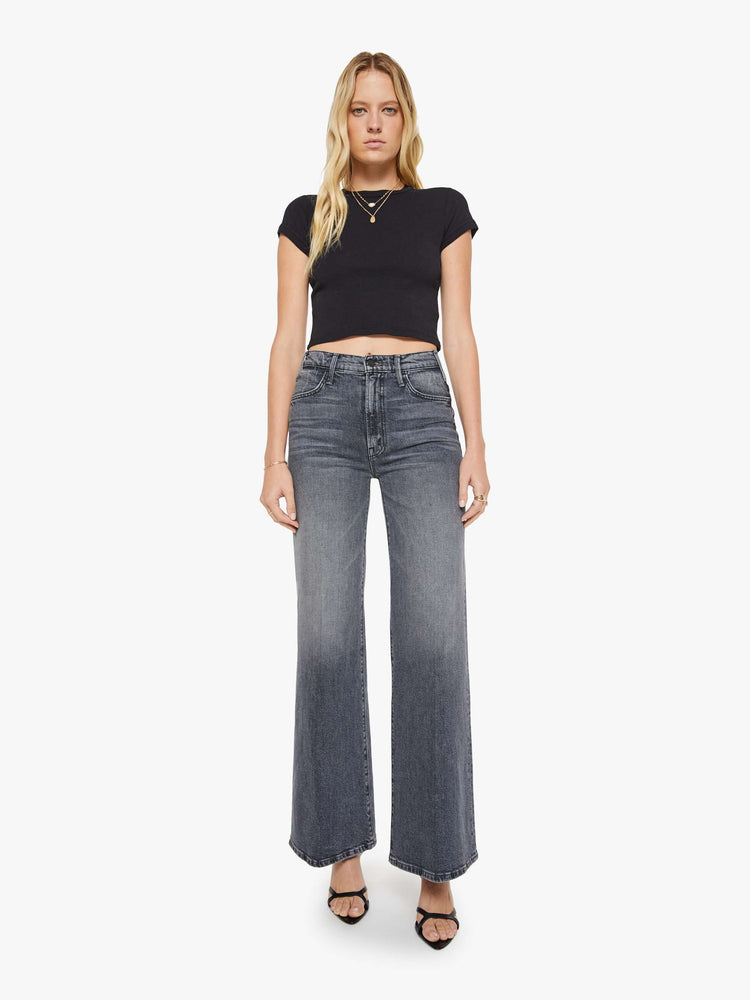 Full body view of a woman in a black shrunken crewneck tee with extra-short sleeves and a cropped length.