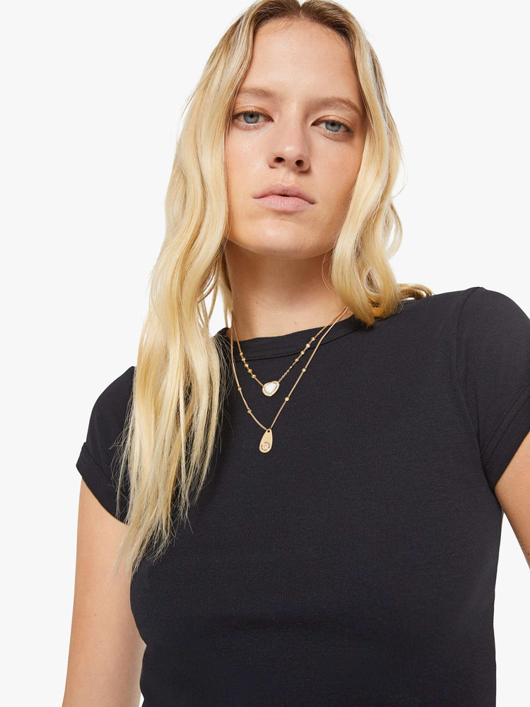 Close up view of a woman in a black shrunken crewneck tee with extra-short sleeves and a cropped length.