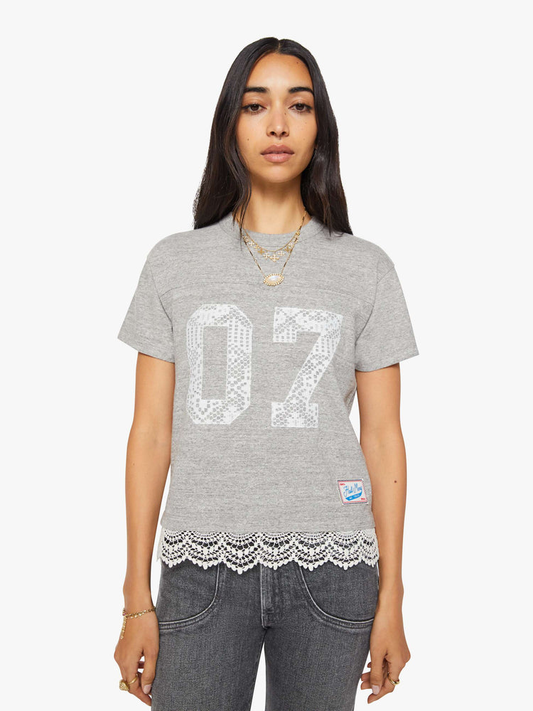 Front view of a woman in a heather grey with white lace applique on the front and lace trim oversized crewneck tee is designed with drop shoulders, short sleeves and a boxy fit.