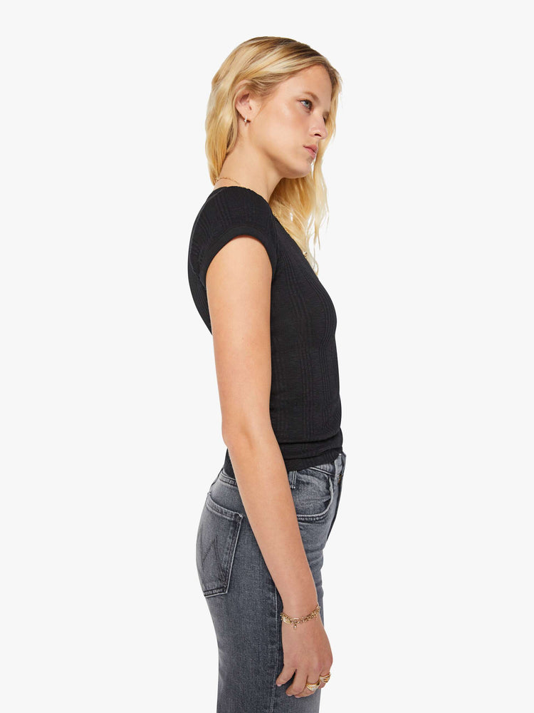 Side view of a woman in a black tee with extra-short sleeves and a narrow fit.