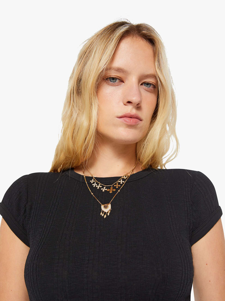 Close up view of a woman in a black tee with extra-short sleeves and a narrow fit.