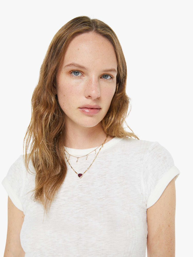 Close up view of a woman in a white  shrunken crewneck tee with extra-short sleeves and a narrow fit. 