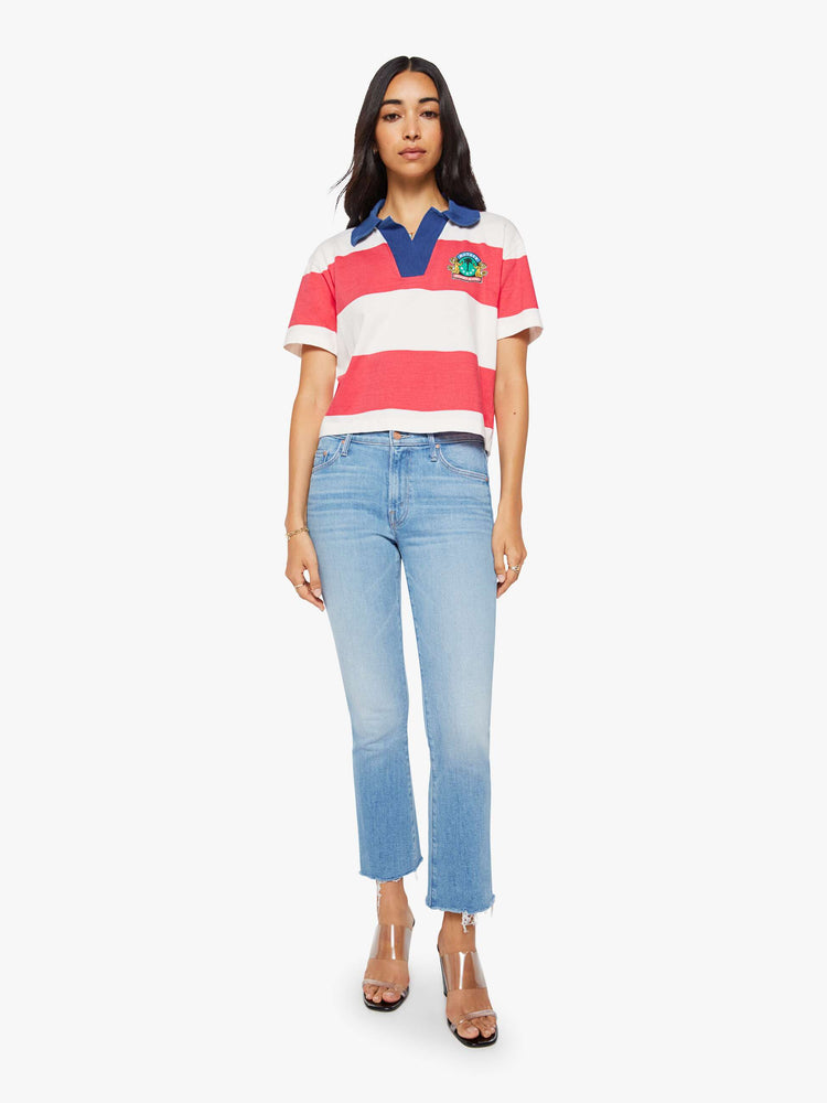 Full body view of a woman in a collared top with short sleeves, a V-neck and a loose fit.