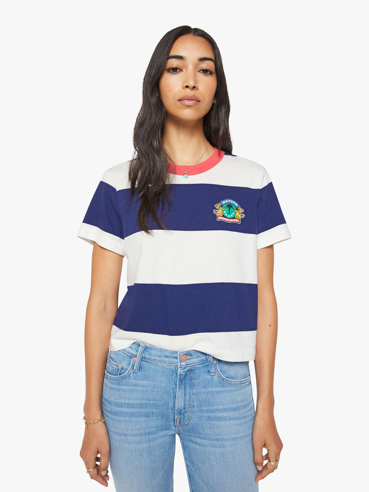 Front view of the woman in a white and navy stripes with a faded red trim collar tee with a chest  inspired by a country club logo.