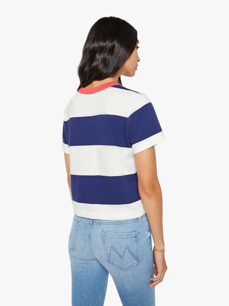 Back view of the woman in a white and navy stripes with a faded red trim collar tee with a chest  inspired by a country club logo.