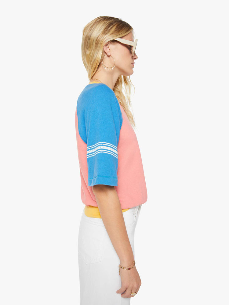 Side view of a woman in a pale pink with blue sleeves and yellow trim sweatshirt and features a crackle-printed 51 on the chest and white stripes on the sleeves.