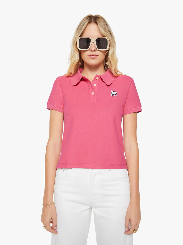 Front view of a woman in pink polo shirt with a three-button placket, short sleeves, split hem and a slightly shrunken fit.