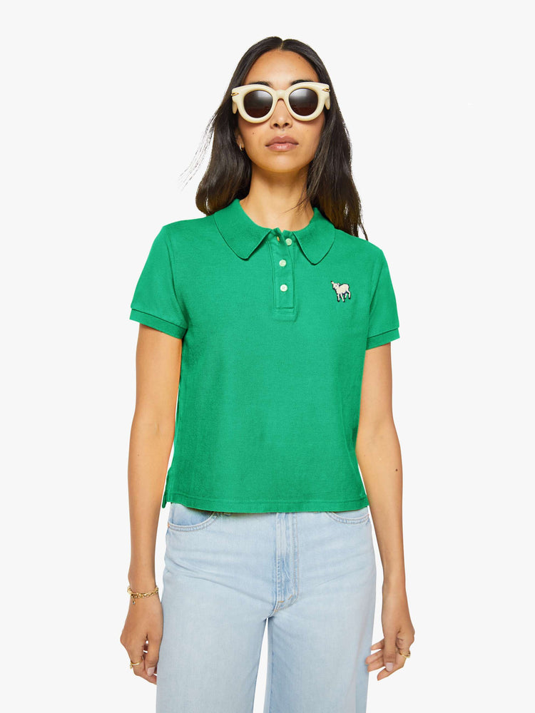 Front view of a woman in green polo shirt with a three-button placket, short sleeves, split hem and a slightly shrunken fit.