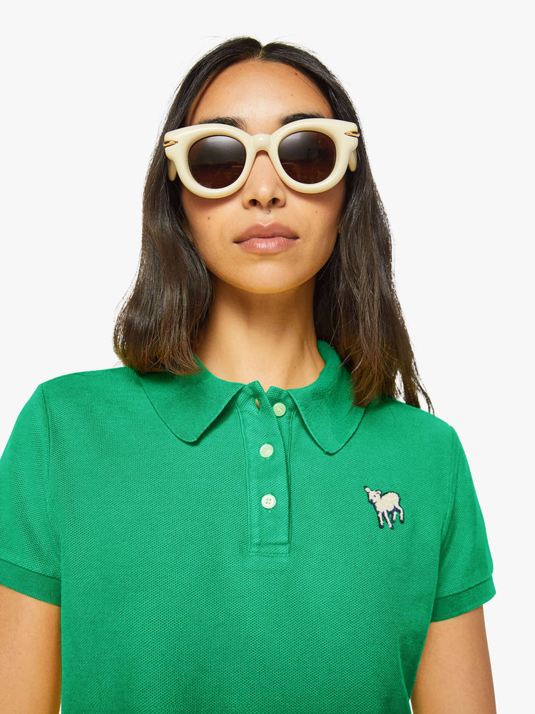 Close up view of a woman in green polo shirt with a three-button placket, short sleeves, split hem and a slightly shrunken fit.