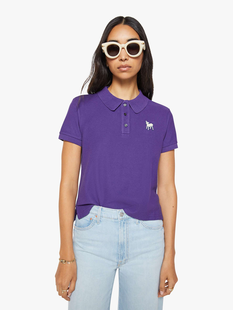 Front view of a woman in purple polo shirt with a three-button placket, short sleeves, split hem and a slightly shrunken fit.