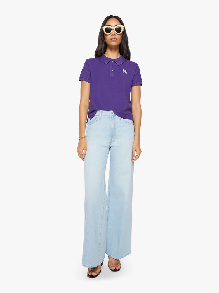 Front view of a woman in purple polo shirt with a three-button placket, short sleeves, split hem and a slightly shrunken fit.