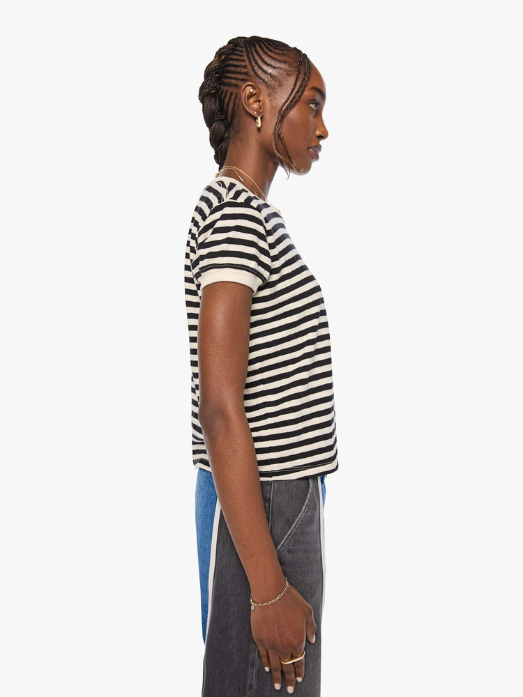 Side view of a woman in a black and cream stripes tee features a mouth patch with MOTHER's name in yellow on the hip.