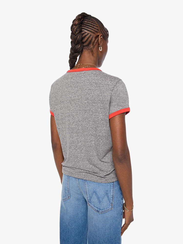 Back view of a woman in a heathered grey tee features red trim and an applique text graphic with small metal studs on the front.