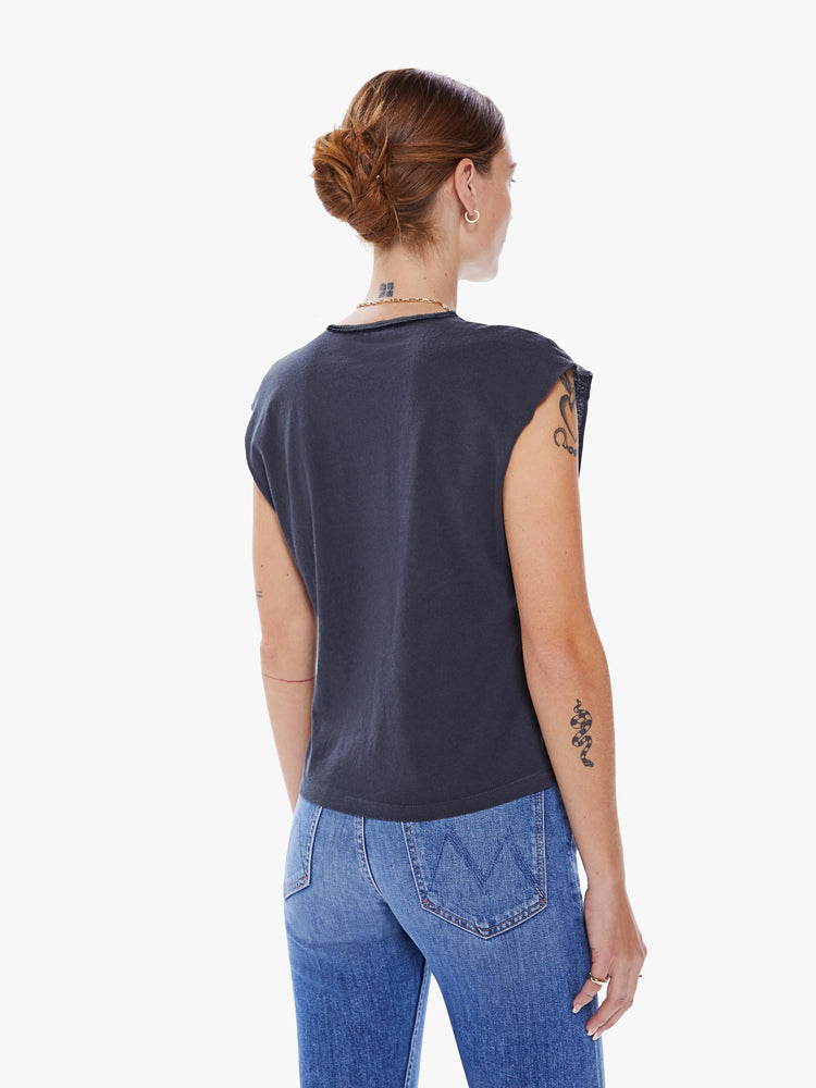 Back view of a woman black crewneck tee with raw cutoff sleeves and a clean hem with a festival graphic.