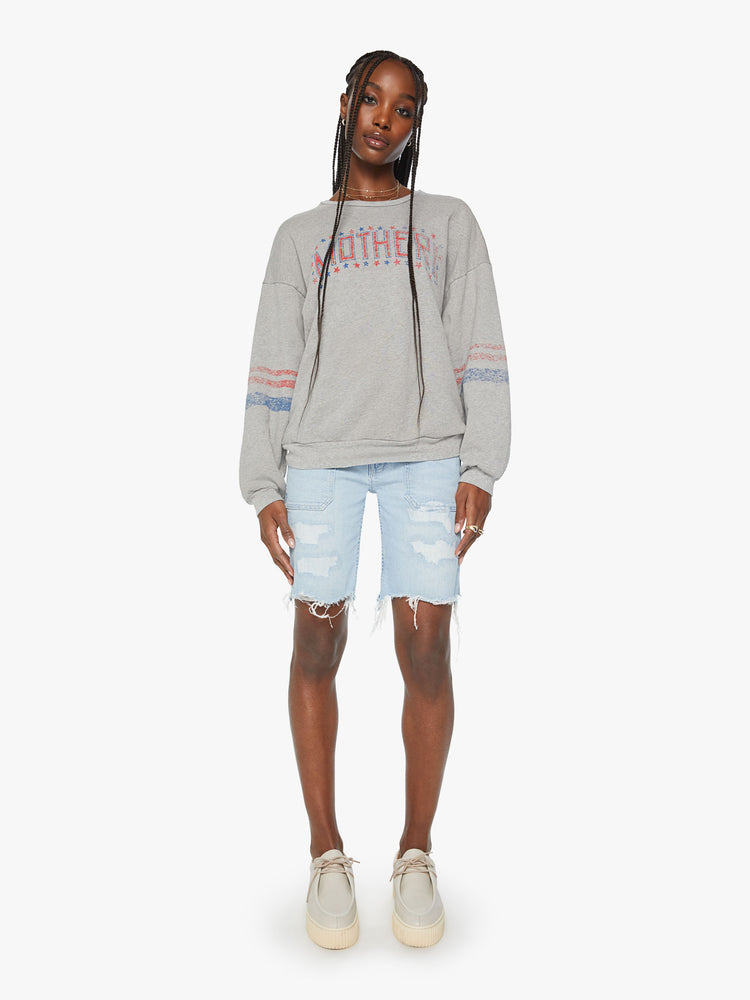 Full body view of a women crewneck sweatshirt with dropped sleeves and a relaxed fit in a light grey color with American flag-inspired stars and stripes.