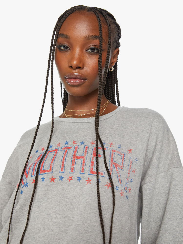 Close up view of a women crewneck sweatshirt with dropped sleeves and a relaxed fit in a light grey color with American flag-inspired stars and stripes.