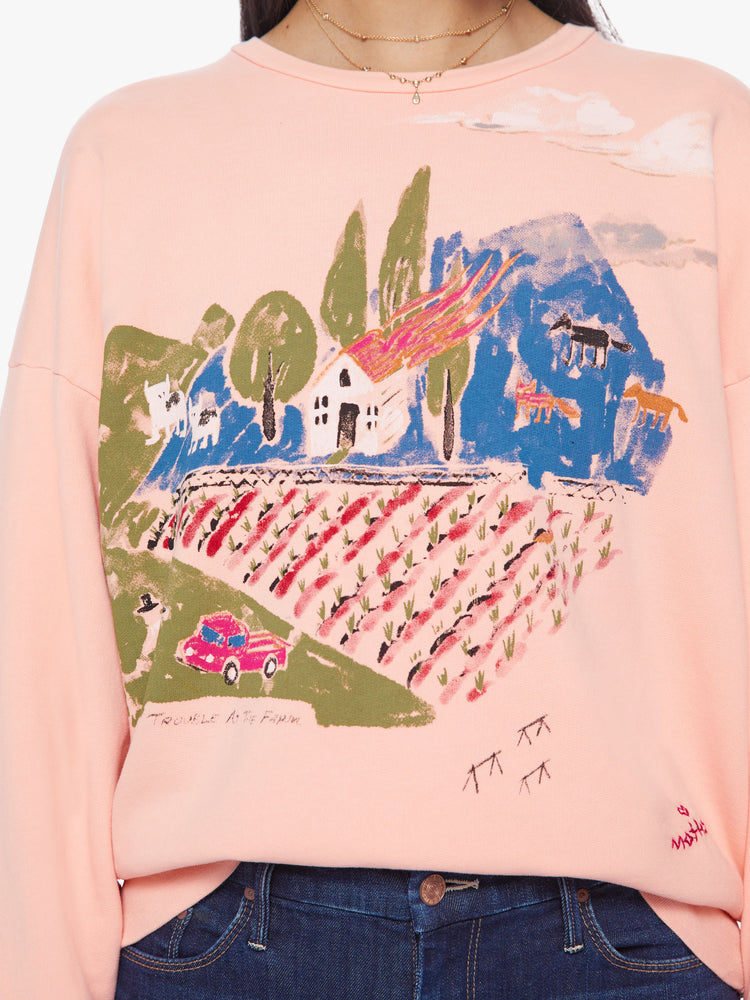 Close up view of a woman light pink sweatshirt with dropped sleeves with a hand-drawn doodle of a barn in flames.
