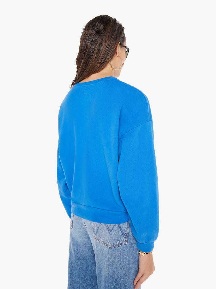 Back view of a woman wearing a bright blue oversized sweatshirt, paired with a medium blue wash jean.