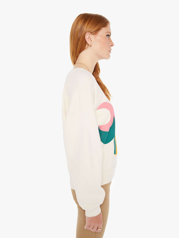 Side view of a womens ivory crew neck sweatshirt featuring a large colorful graphic.