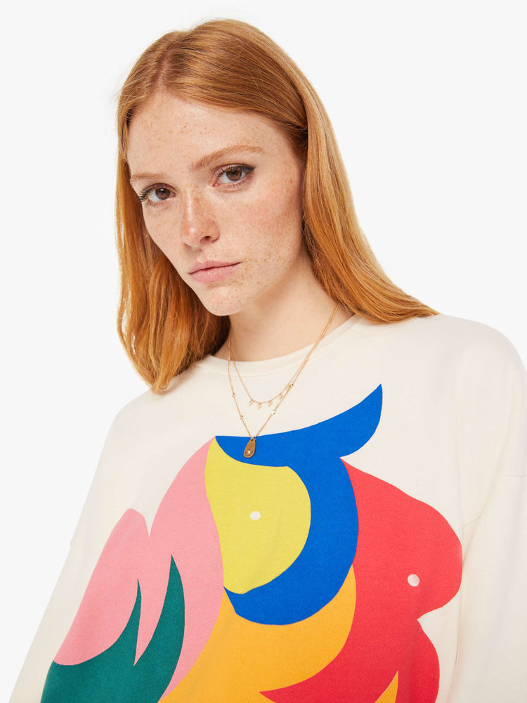 Front close up view of a womens ivory crew neck sweatshirt featuring a large colorful graphic.
