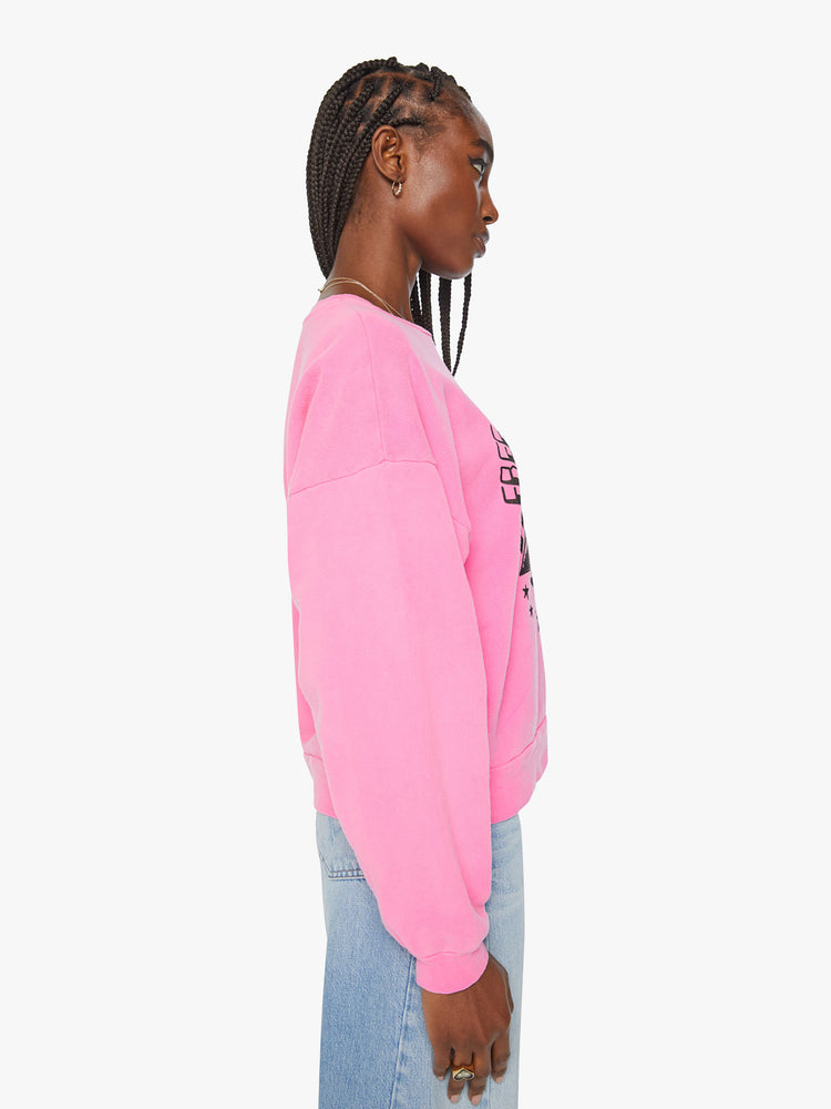 Side view of a woman crewneck sweatshirt with dropped sleeves in hot pink with black graphic.