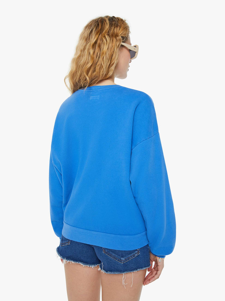 A back view of a woman wearing a blue sweatshirt featuring an oversized fit, paired with dark blue denim short.