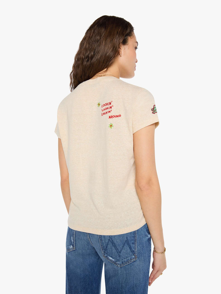 Back view of a woman in cream with maroon applique text and colorful embroidery at the chest.