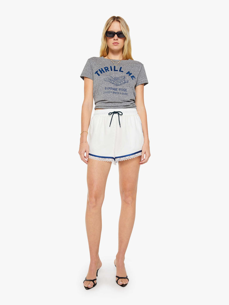 Full body view of a woman in a heathered grey, the tee features a rollercoaster graphic and text in a raised, velvety navy-blue texture on the front.