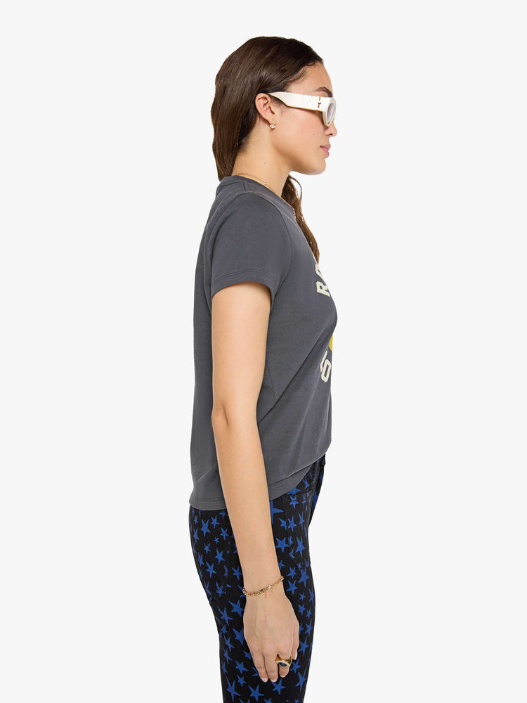 Side view of a woman in faded black tew with a smiley-face graphic and flocked text in white across the chest.