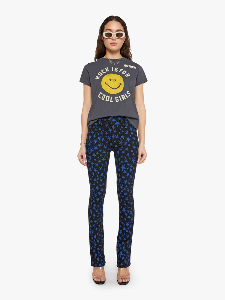 Full body view of a woman in faded black tew with a smiley-face graphic and flocked text in white across the chest.